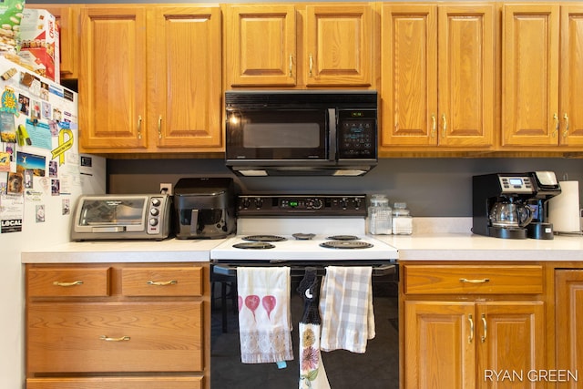 kitchen featuring electric range, brown cabinets, freestanding refrigerator, light countertops, and black microwave