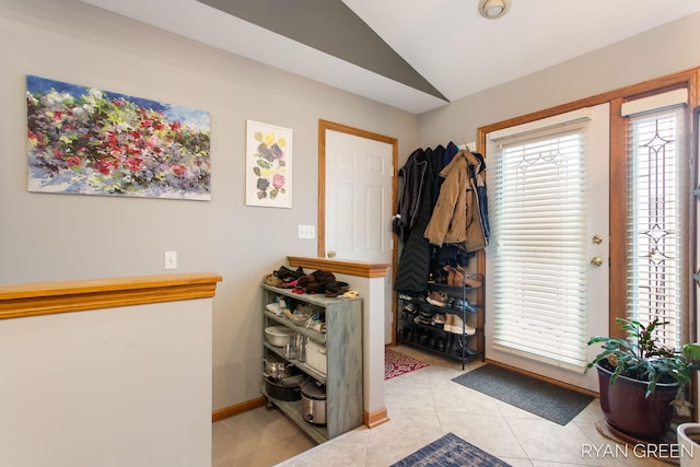 entryway featuring vaulted ceiling, light tile patterned floors, and baseboards