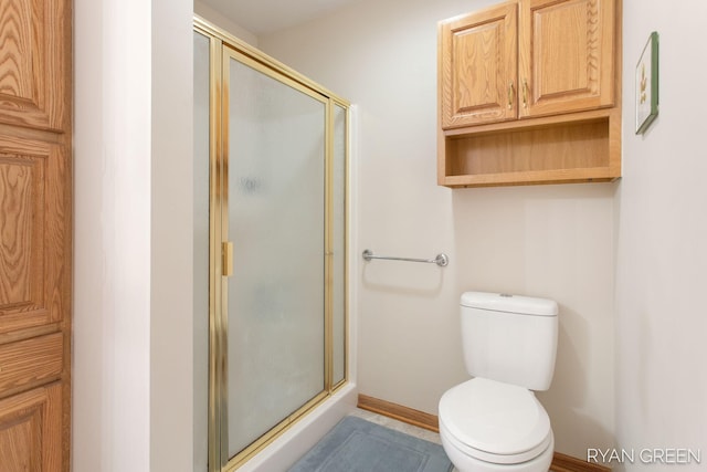 bathroom featuring toilet, a shower stall, and baseboards