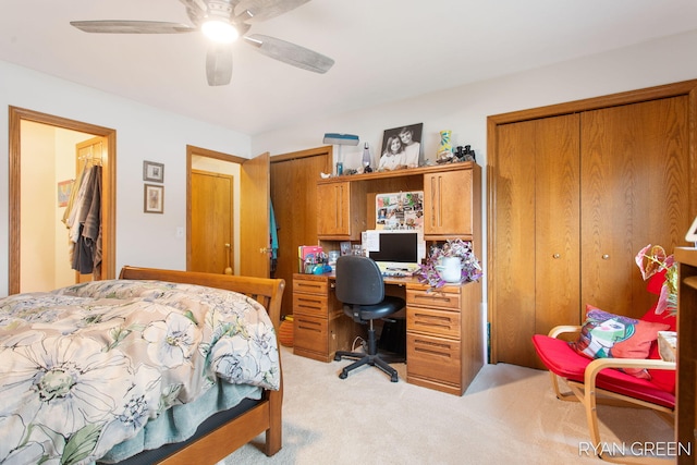 bedroom with light carpet, ceiling fan, and two closets