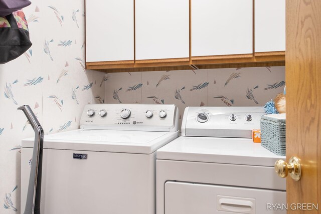 washroom featuring cabinet space, wallpapered walls, and washer and dryer