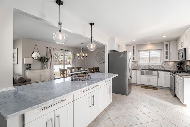 kitchen with a sink, stainless steel appliances, white cabinets, glass insert cabinets, and backsplash