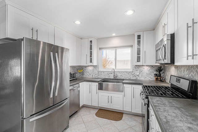 kitchen featuring a sink, stainless steel appliances, dark countertops, and white cabinets