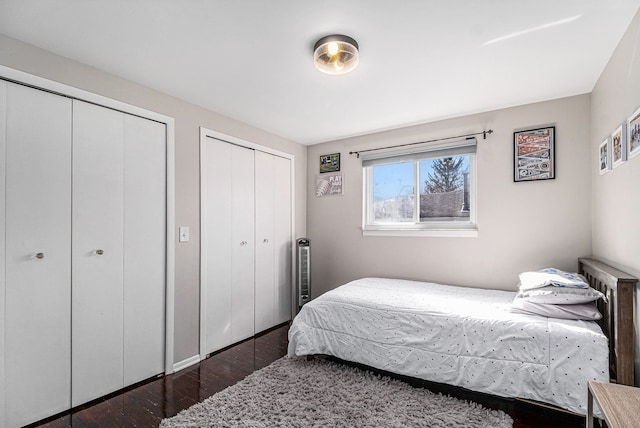 bedroom featuring dark wood-type flooring and two closets