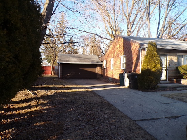 view of side of property featuring brick siding, an outdoor structure, and fence