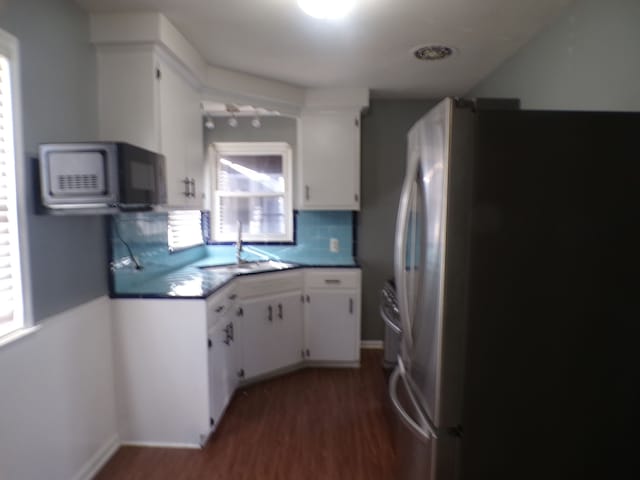 kitchen featuring a sink, white cabinetry, freestanding refrigerator, decorative backsplash, and dark wood finished floors