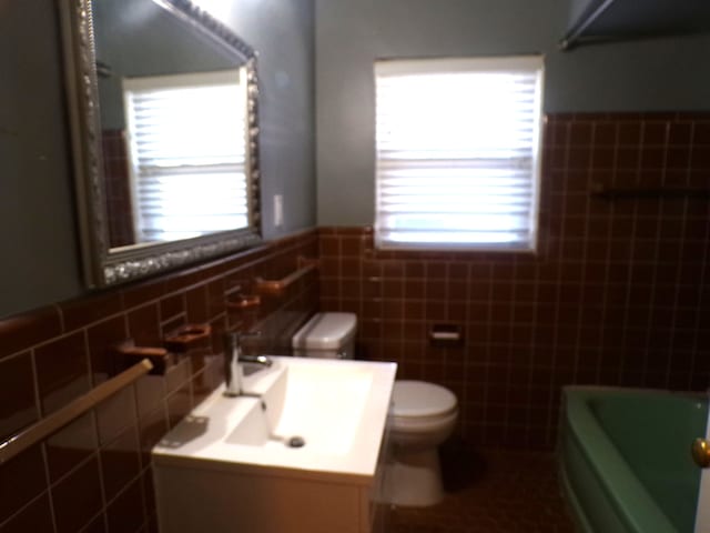 full bathroom with toilet, a bathing tub, a wealth of natural light, and vanity