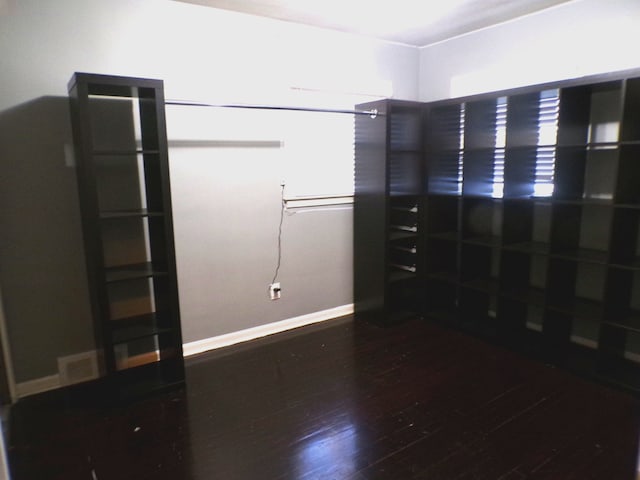 unfurnished room featuring wood-type flooring, visible vents, and baseboards