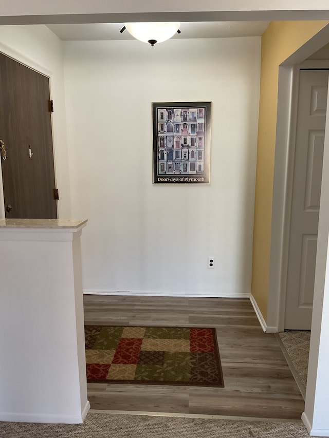 corridor featuring baseboards and wood finished floors