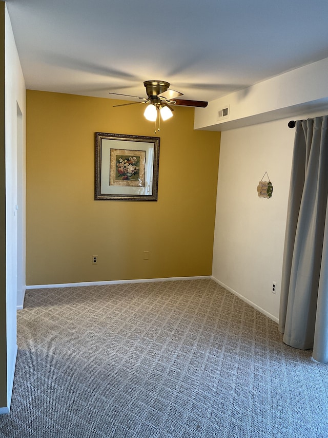 carpeted empty room with a ceiling fan, visible vents, and baseboards