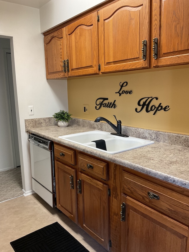 kitchen with dishwashing machine, brown cabinetry, a sink, and light countertops