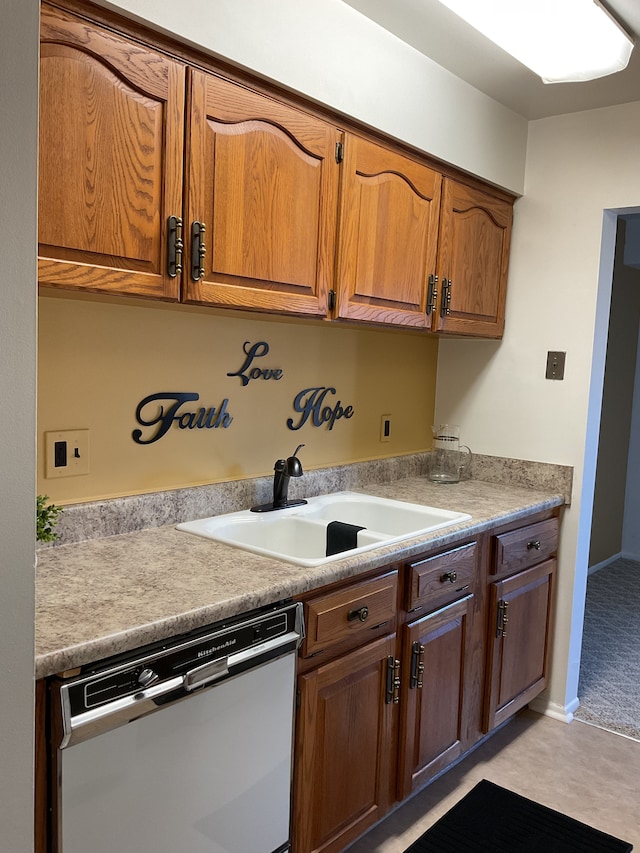 kitchen with dishwashing machine, light countertops, brown cabinetry, a sink, and baseboards