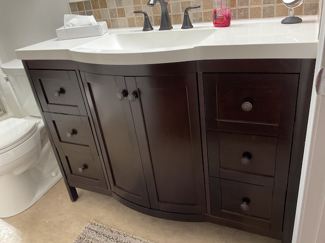 bathroom with decorative backsplash, vanity, and toilet