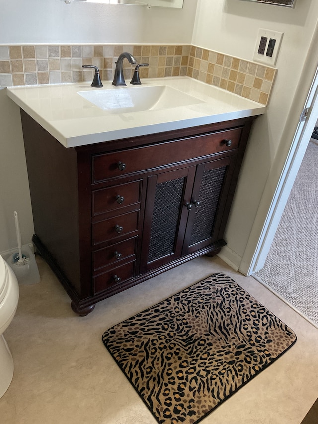 bathroom featuring toilet, backsplash, and vanity