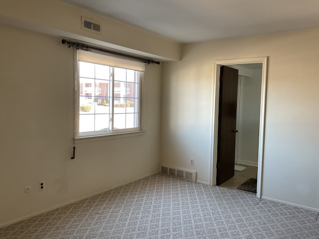 empty room with baseboards, visible vents, and carpet flooring