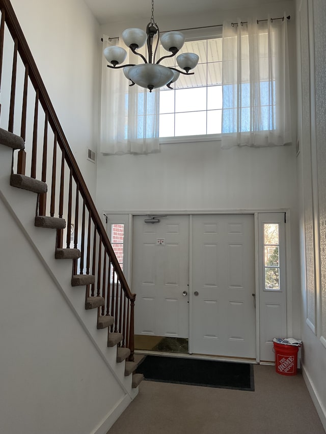 foyer with stairway, a chandelier, visible vents, and a towering ceiling