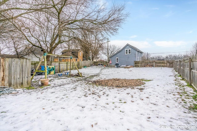 yard layered in snow with a playground and a fenced backyard