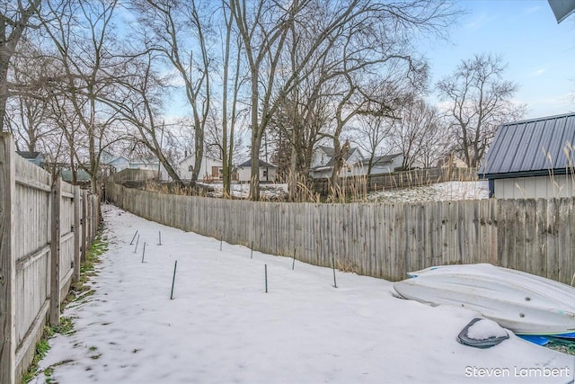 yard layered in snow featuring a fenced backyard