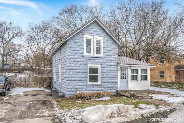 view of front of home featuring metal roof and fence