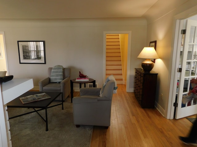 living room with stairs, hardwood / wood-style floors, and baseboards