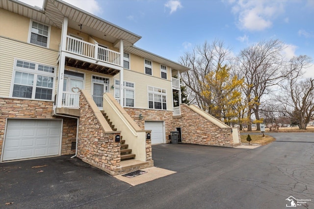 view of front of property with aphalt driveway, an attached garage, and stairs