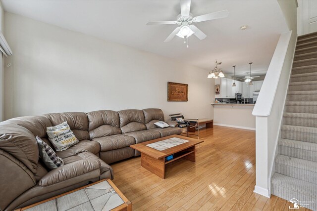 living area featuring light wood-style floors, baseboards, stairway, and a ceiling fan