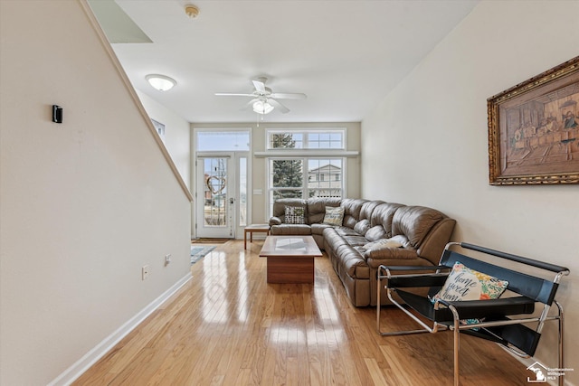 living area with light wood-type flooring, a ceiling fan, and baseboards