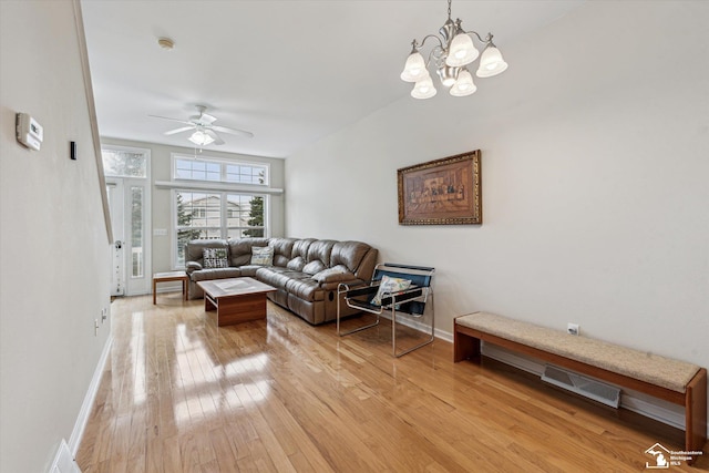 living room featuring light wood-style flooring, visible vents, baseboards, and ceiling fan with notable chandelier