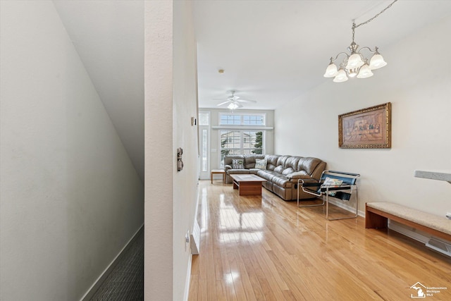 living area with light wood-style flooring, visible vents, baseboards, and ceiling fan with notable chandelier