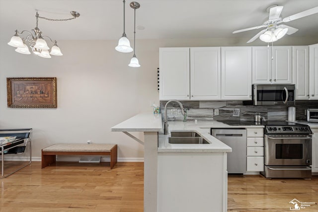 kitchen with a peninsula, appliances with stainless steel finishes, white cabinets, and a sink