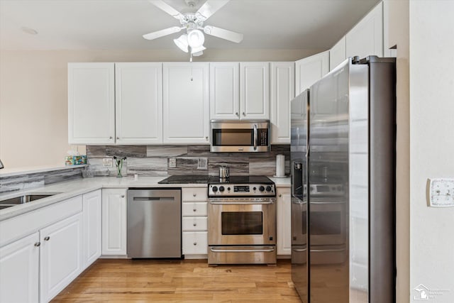 kitchen featuring appliances with stainless steel finishes, light wood-type flooring, white cabinetry, and a sink