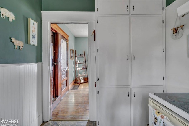 corridor featuring a wainscoted wall and wood finished floors