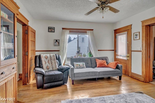 living area featuring light wood finished floors, a ceiling fan, and a textured ceiling