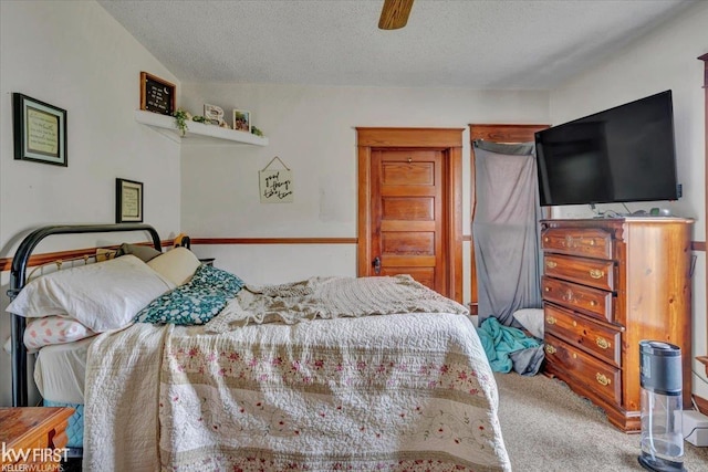 carpeted bedroom with ceiling fan and a textured ceiling