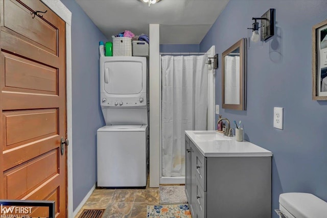 full bath with stacked washer and dryer, visible vents, toilet, curtained shower, and vanity