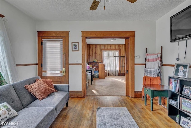 living area with a textured ceiling, a ceiling fan, and hardwood / wood-style floors