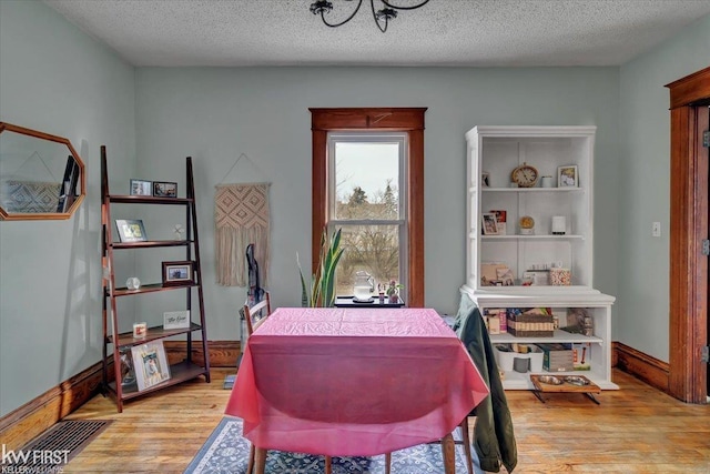 dining area with a textured ceiling, wood finished floors, and baseboards