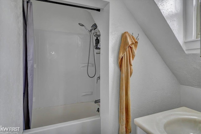 full bathroom featuring shower / bath combination with curtain, a textured wall, and a sink