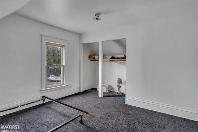 unfurnished bedroom featuring carpet, lofted ceiling, and baseboards