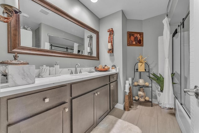 full bathroom with combined bath / shower with glass door, visible vents, vanity, and tile patterned floors