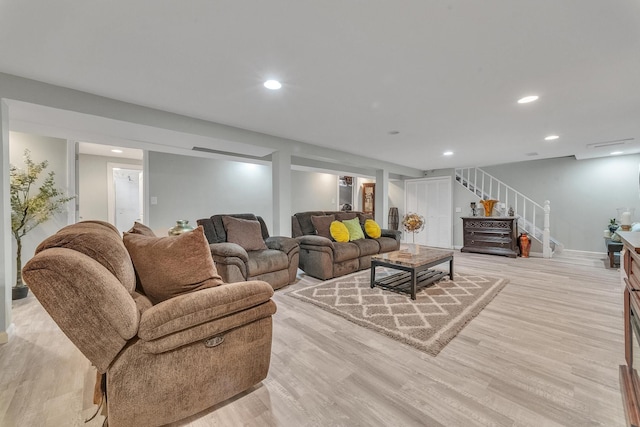 living area with recessed lighting, baseboards, light wood-style flooring, and stairs