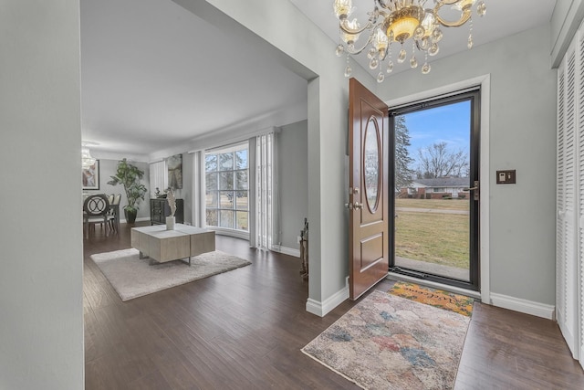 foyer entrance featuring baseboards, dark wood-type flooring, and an inviting chandelier