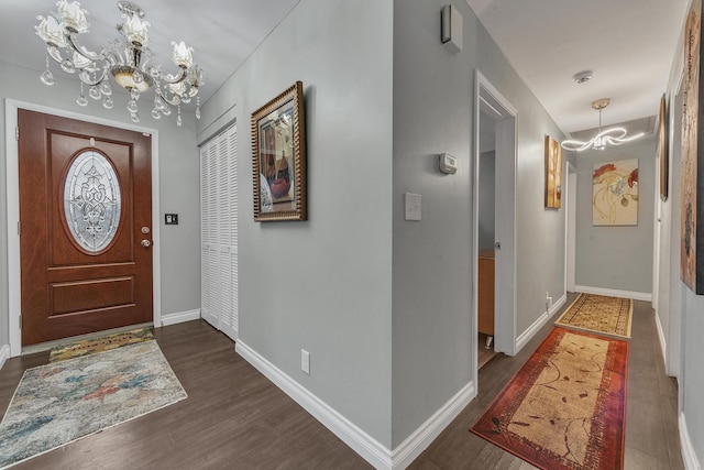 entryway with a chandelier, dark wood-style floors, and baseboards