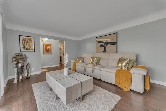 living area featuring a notable chandelier, baseboards, and dark wood-type flooring