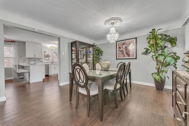 dining area with baseboards, dark wood-type flooring, and an inviting chandelier