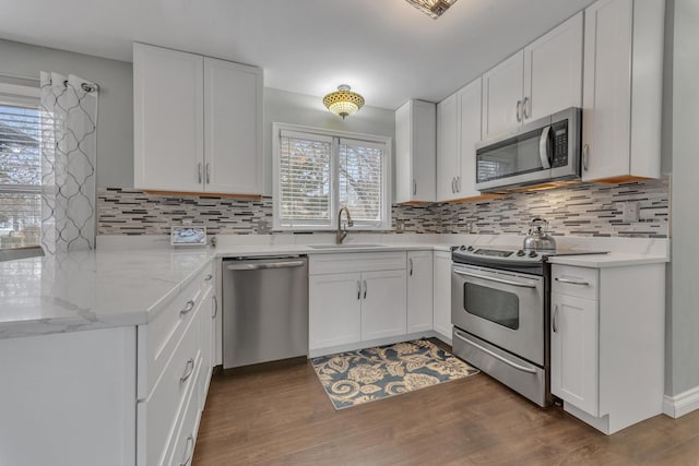 kitchen with a sink, stainless steel appliances, dark wood-style floors, and decorative backsplash