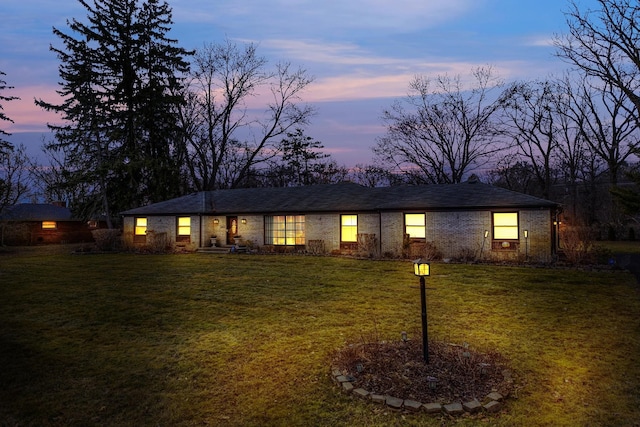 ranch-style house featuring a yard and brick siding