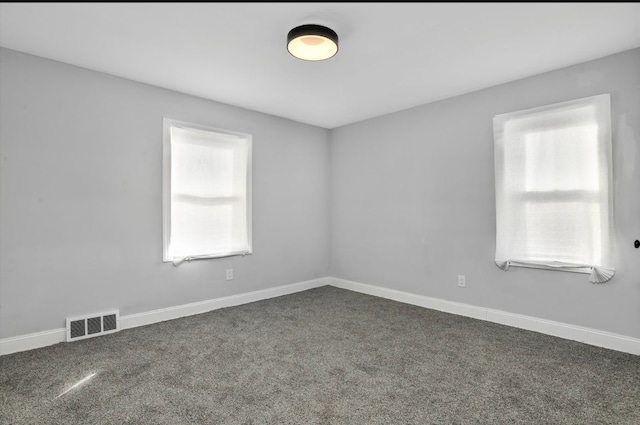 spare room featuring a healthy amount of sunlight, baseboards, visible vents, and carpet flooring