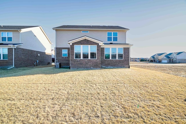 view of front facade featuring a front lawn, central AC unit, and brick siding