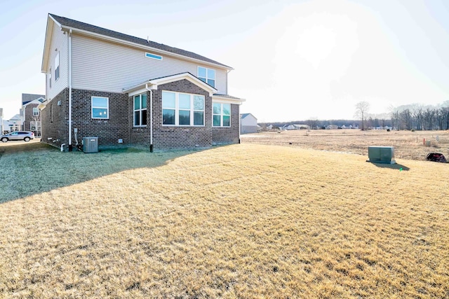 exterior space with cooling unit, brick siding, and a yard